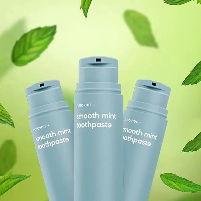 Toothpaste bottles with smooth mint flavor and fluoride formula, surrounded by fresh green leaves.