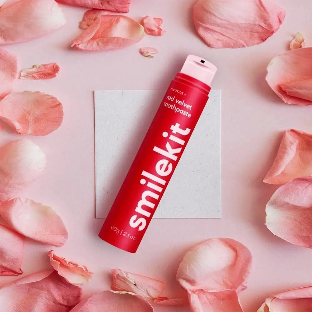 Smilekit toothpaste with fluoride, surrounded by pink petals.