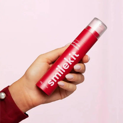 Smilekit toothpaste in a red tube held in hand, featuring unique flavors and fluoride protection.