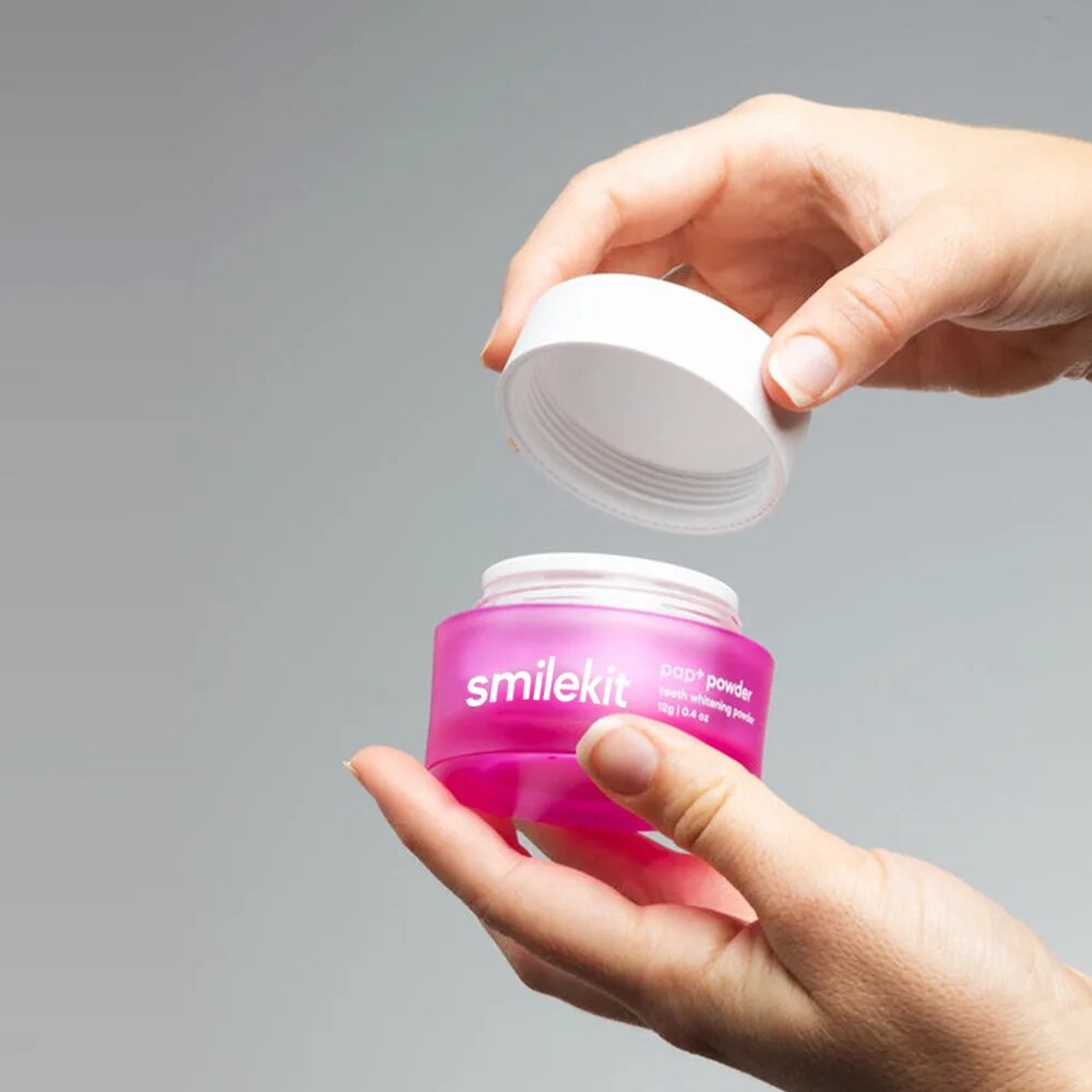 Smilekit PAP+ Whitening Powder in a pink container being opened, designed for effective teeth whitening.