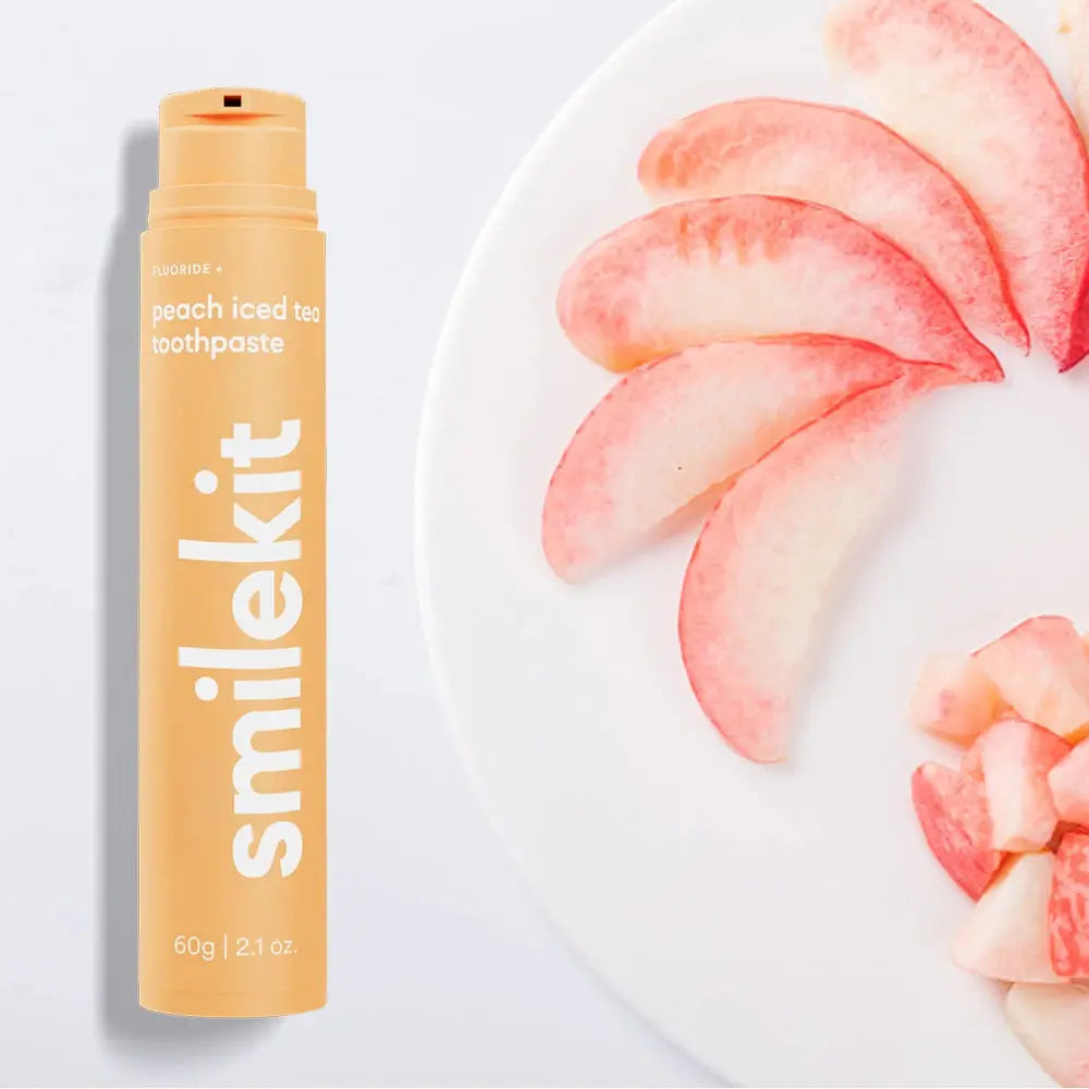 Smilekit peach iced tea toothpaste with fresh peach slices on a plate.