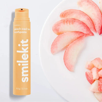 Smilekit peach iced tea toothpaste with fresh peach slices on a plate.