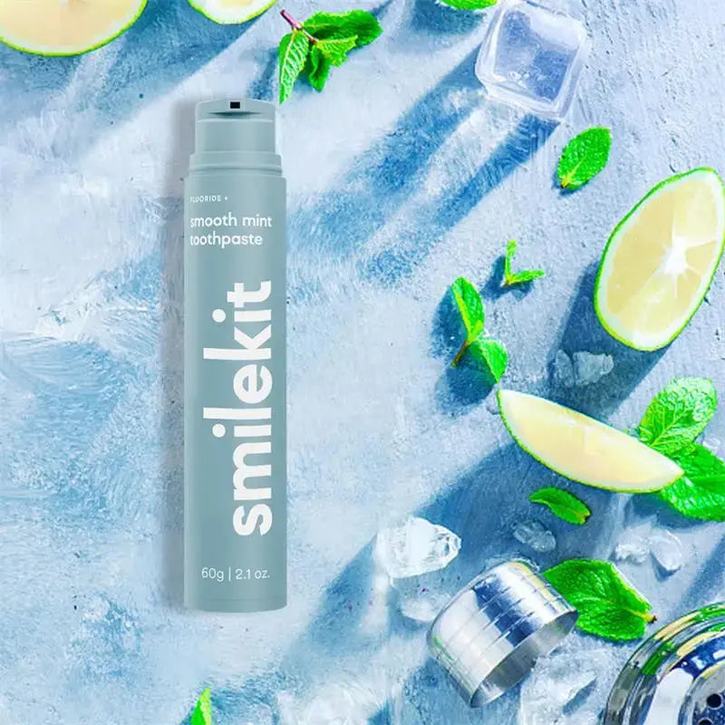 Smilekit toothpaste featuring smooth mint flavor amidst fresh mint and lime slices.